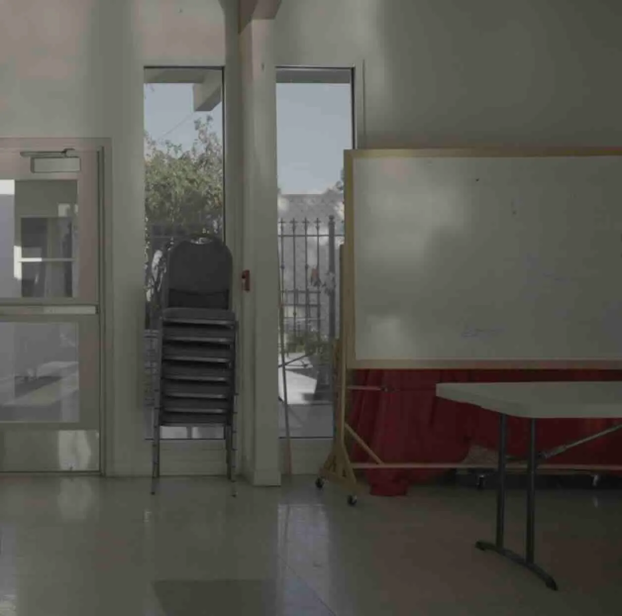 A stack of chairs next to a blank dry-erase board.