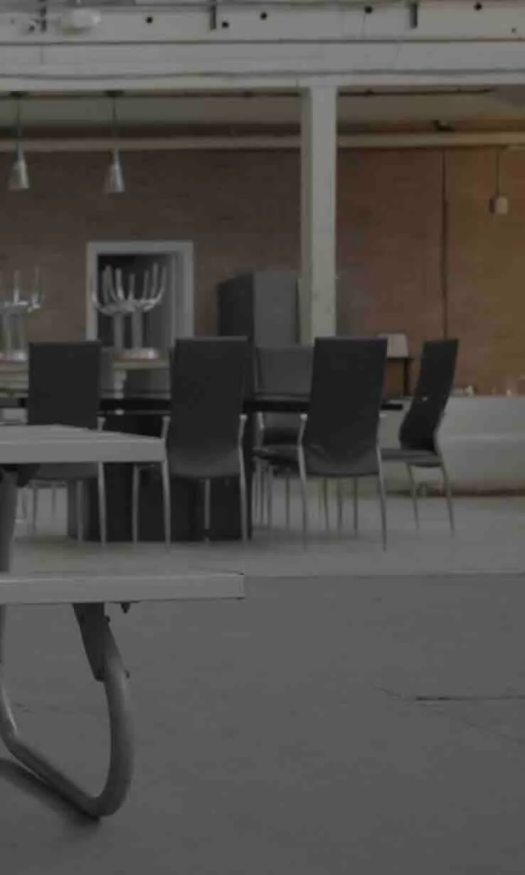A table in a cafeteria with a number of unused chairs around it.